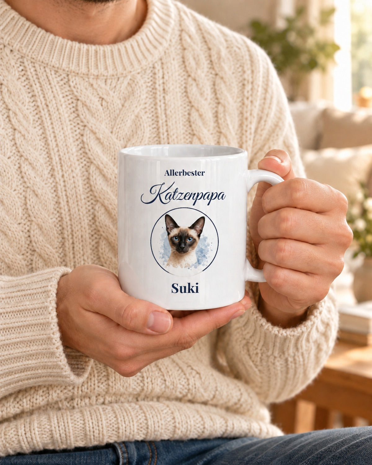 Weiße Tasse Allerbester Katzenpapa mit Siamkatze im Medaillon und Namen Suki, gehalten von einem Mann im Zopfstrickpullover