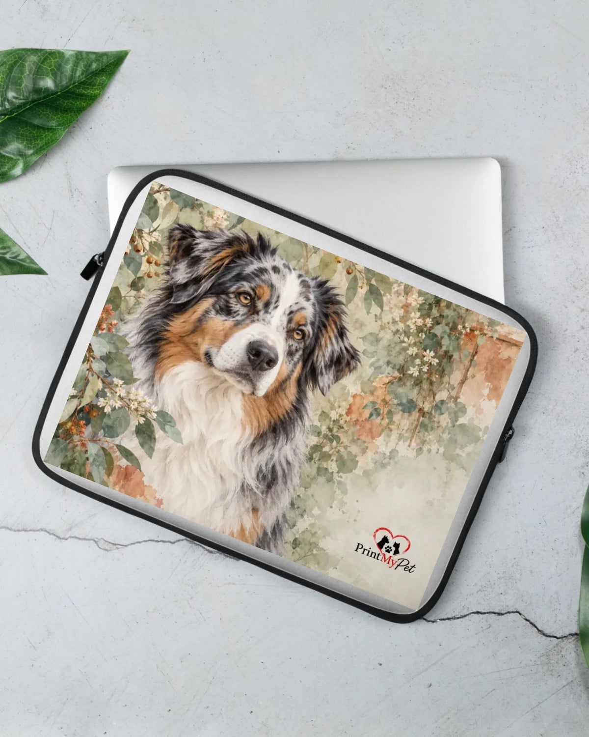 Laptophülle mit Australian Shepherd im Aquarell-Stil auf hellem Stein neben einem Laptop