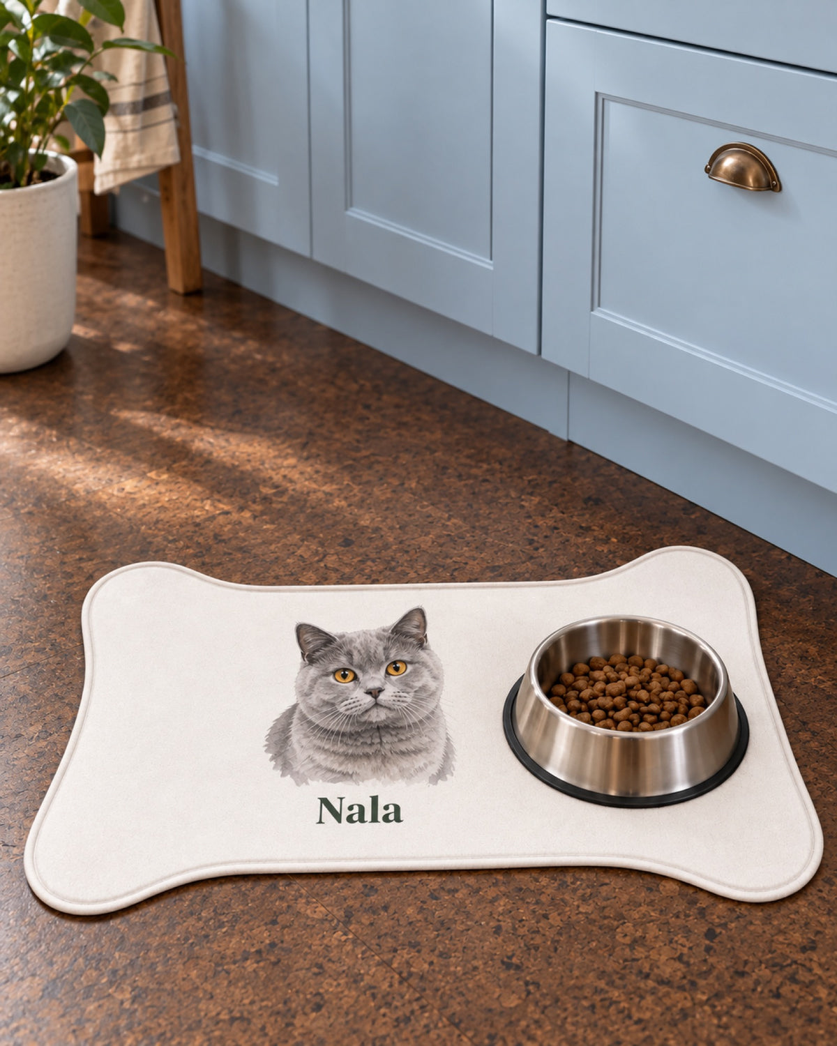 Kleine knochenförmige Futtermatte mit graue Britisch Kurzhaar Katze Nala auf einem dunklen Korkboden vor hellblauer Küchenschrankwand