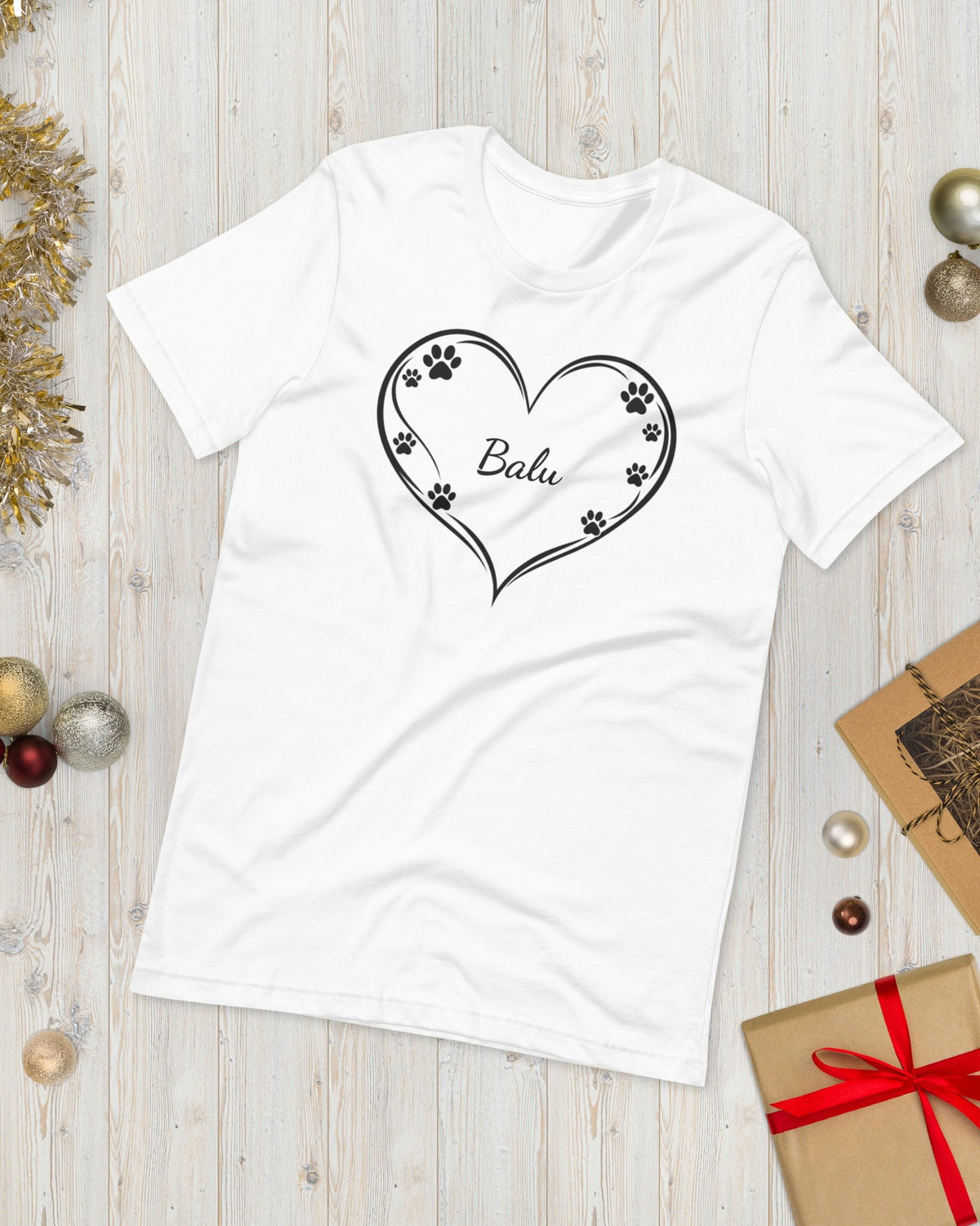 T-Shirt Herz mit Pfoten in Weiß mit Namen Balu, weihnachtlich auf Holz gelegt
