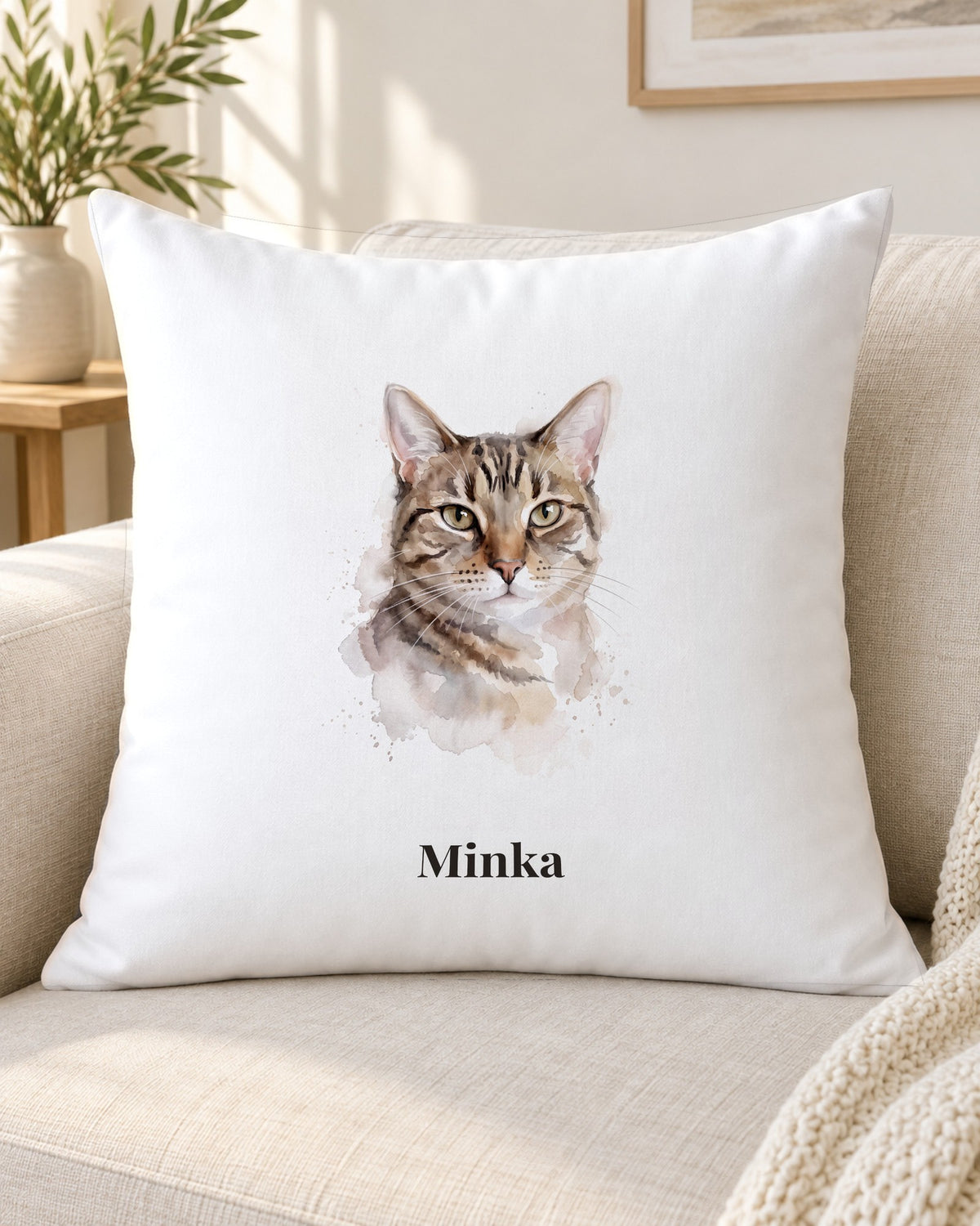Kissen mit Katzenportrait im Aquarell-Stil und Namen Minka auf dem Sofa