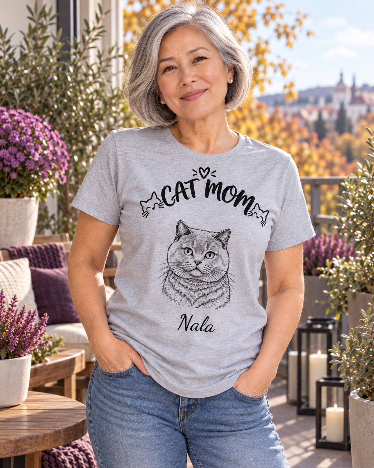 Frau im graumelierten Cat Mom T-Shirt mit Britisch Kurzhaar Nala als monochromer Linienzeichnung auf einer violetten Loggia