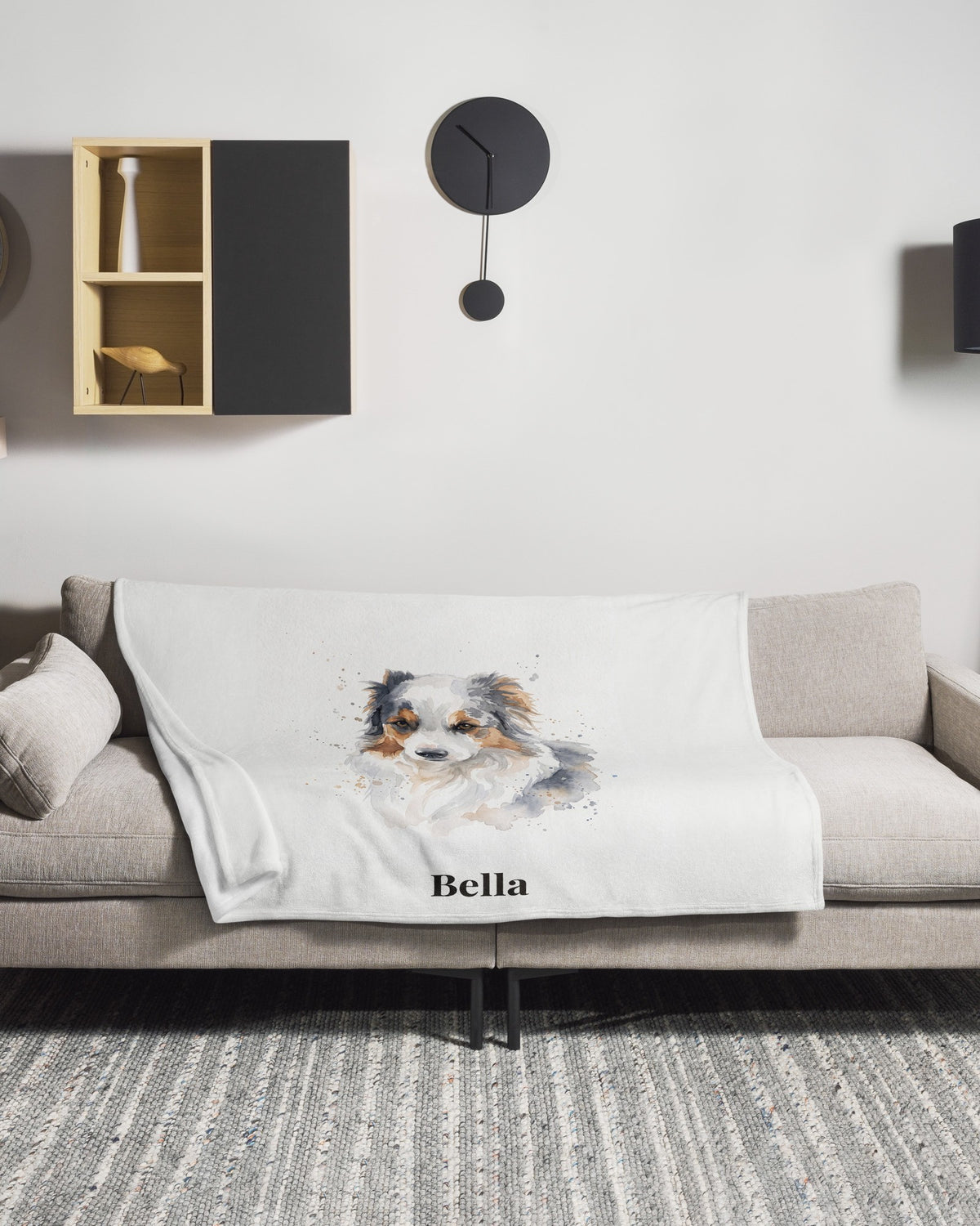 Kuscheldecke mit Hundeportrait im Aquarell-Stil und Namen Bella auf dem Sofa