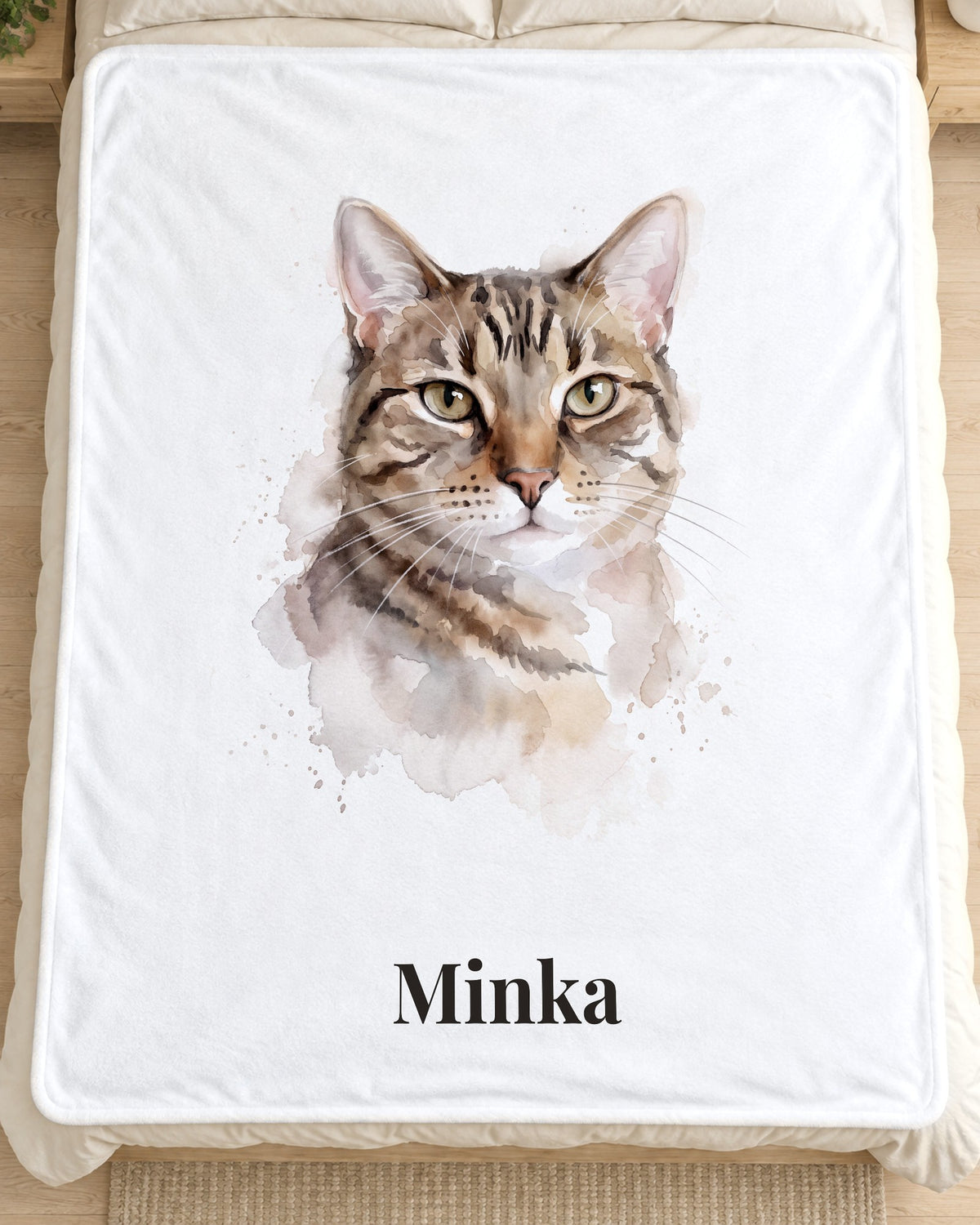 Kuscheldecke mit Katzenportrait im Aquarell-Stil und Namen Minka auf dem Bett