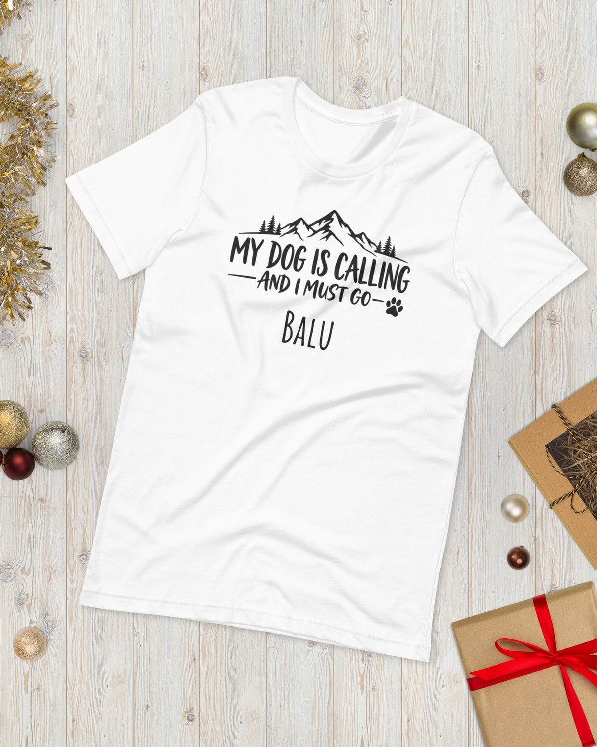 T-Shirt My Dog Is Calling in Weiß mit Namen Balu, weihnachtlich auf Holz gelegt