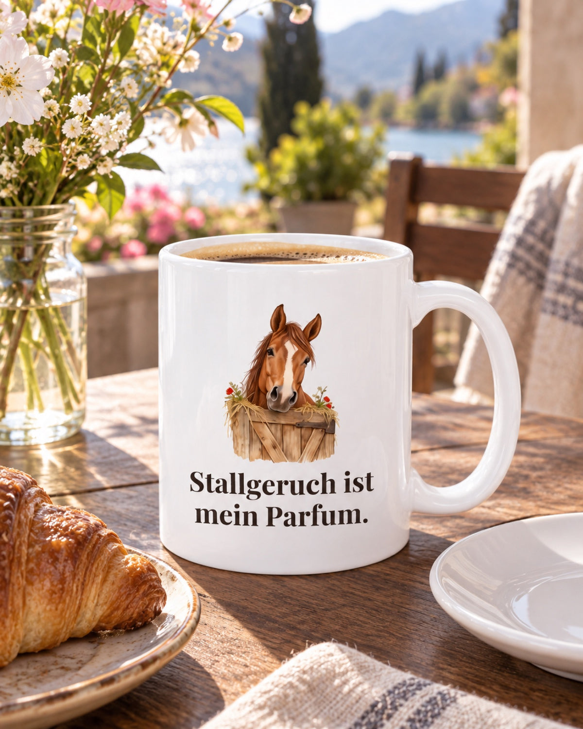 Weiße Keramiktasse Pferdetasse mit Spruch: Stallgeruch ist mein Parfum. auf einem Cafétisch im Frühling