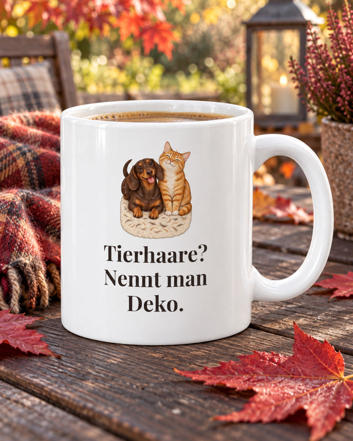 Weiße Keramiktasse Tasse mit Spruch: Tierhaare? Nennt man Deko. auf einem Gartentisch mit Herbstlaub